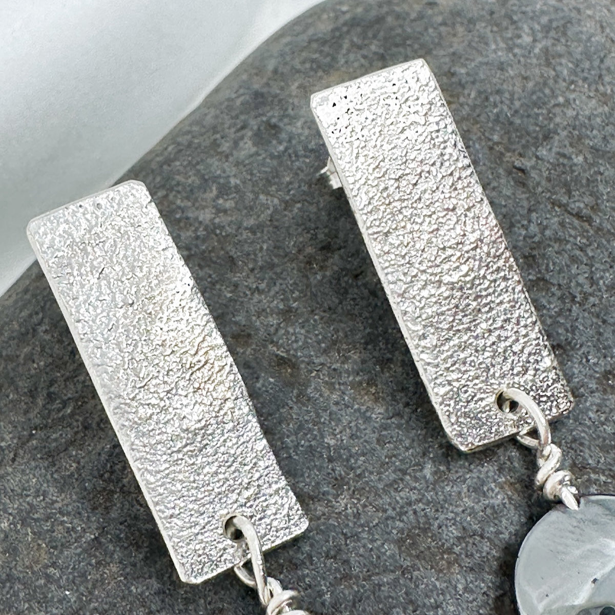 close up. Handmade sterling silver hematite drop earrings with minimalist sculptural design.