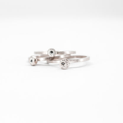 three simple silver stacking rings with each a set black diamond