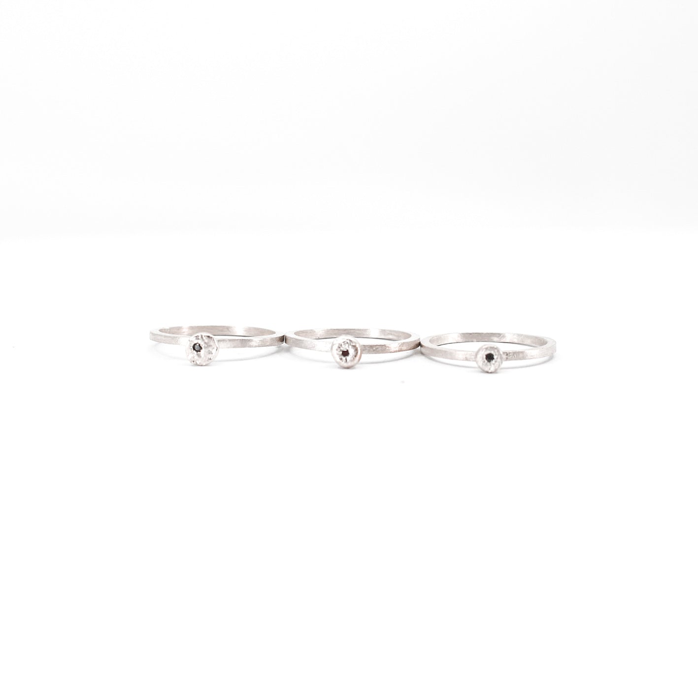 three simple silver stacking rings with each a set black diamond